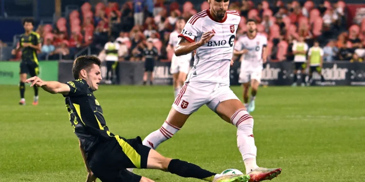 Columbus Crew's Sean Zawadzki, left, strips the ball from Toronto FC's Theo Corbeanu during second-half MLS soccer action in Toronto, Saturday, Aug. 16, 2025. (Jon Blacker/The Canadian Press via AP) (ASSOCIATED PRESS)